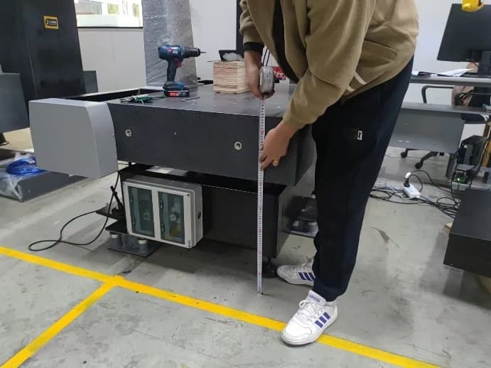 Polaris Classic installation guide photograph showing an engineer checking the CMM table height with a tape measure